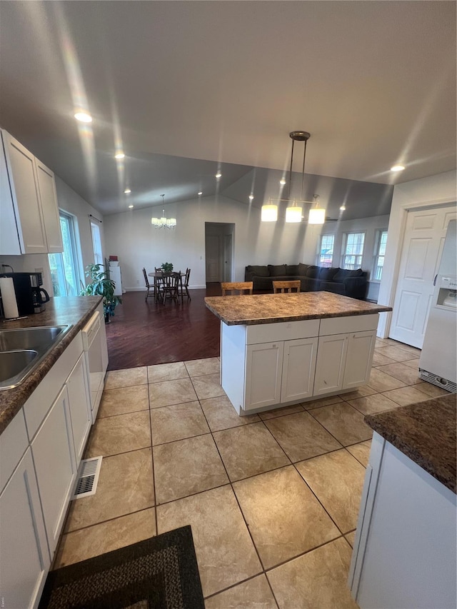 kitchen with white cabinetry, visible vents, a sink, dark countertops, and open floor plan