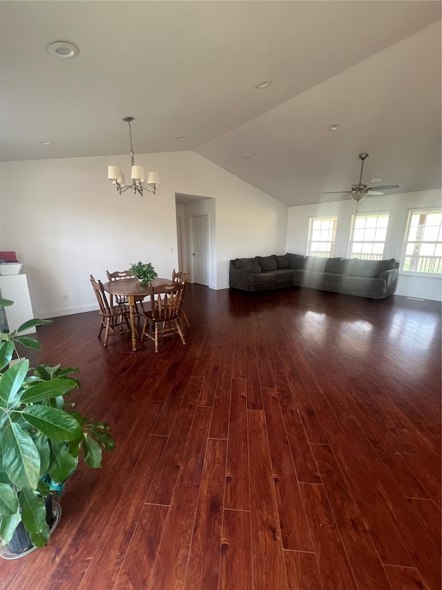 dining space featuring dark wood-type flooring, ceiling fan with notable chandelier, baseboards, and vaulted ceiling