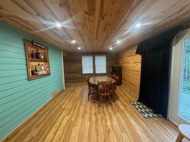 dining space featuring wooden walls, wood ceiling, and light wood-type flooring