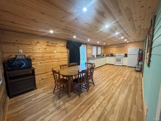 dining room with light wood-type flooring, wooden walls, and recessed lighting