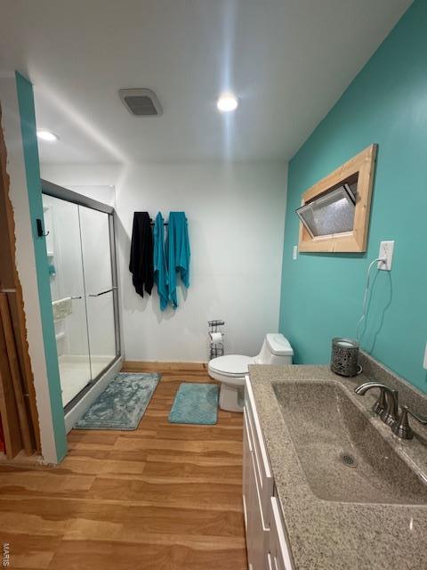 full bathroom with baseboards, toilet, a shower stall, vanity, and wood finished floors