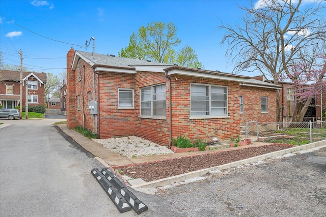 view of side of home featuring fence and brick siding