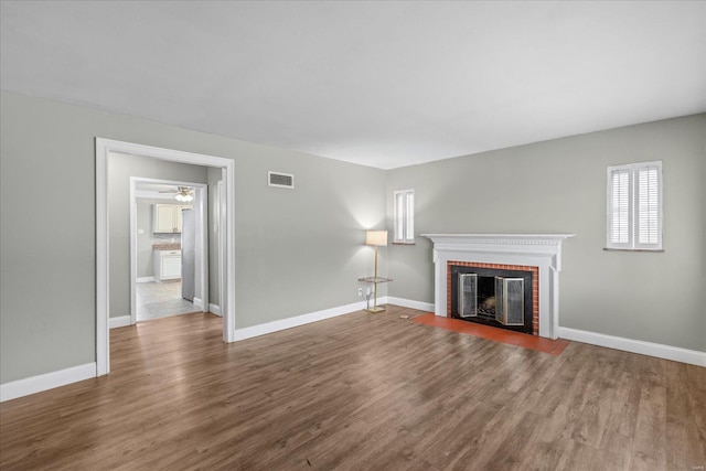 unfurnished living room featuring baseboards, wood finished floors, a fireplace, and visible vents