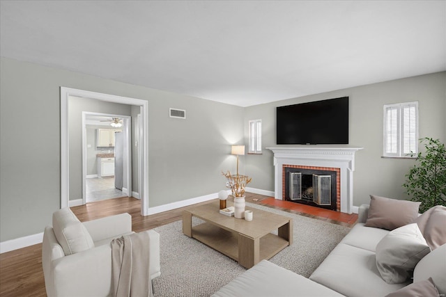 living area with visible vents, baseboards, wood finished floors, and a fireplace