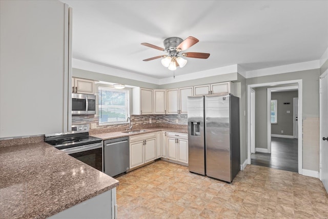 kitchen with a sink, a ceiling fan, stainless steel appliances, backsplash, and cream cabinets