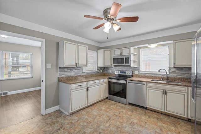 kitchen with appliances with stainless steel finishes, decorative backsplash, a sink, and plenty of natural light