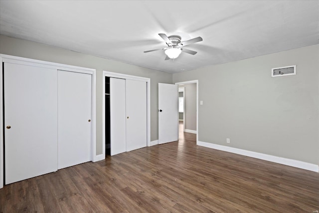unfurnished bedroom with visible vents, baseboards, multiple closets, and wood finished floors