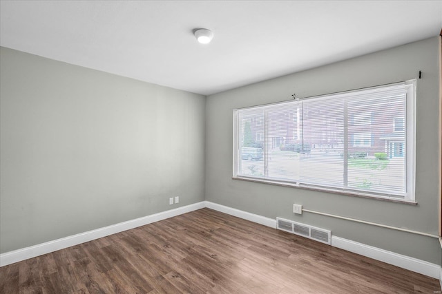 empty room featuring visible vents, baseboards, and wood finished floors