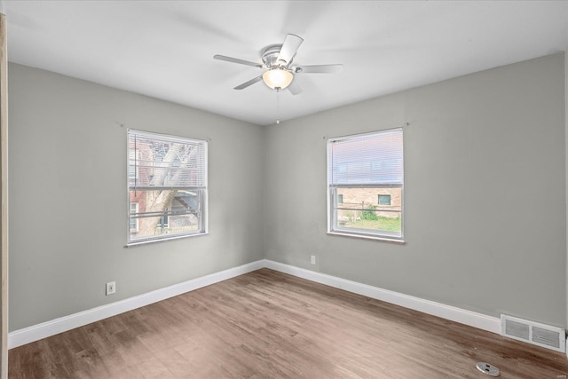 spare room with visible vents, baseboards, and wood finished floors