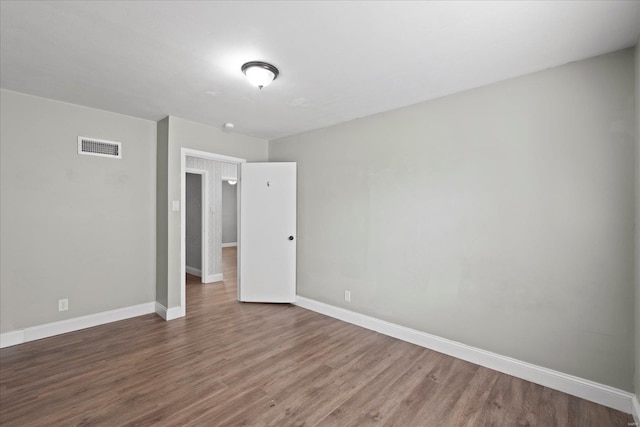 unfurnished bedroom with wood finished floors, baseboards, and visible vents