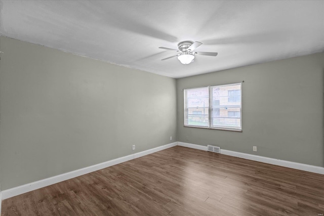 unfurnished room with visible vents, ceiling fan, wood finished floors, and baseboards