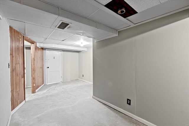 finished below grade area featuring visible vents, baseboards, and a drop ceiling
