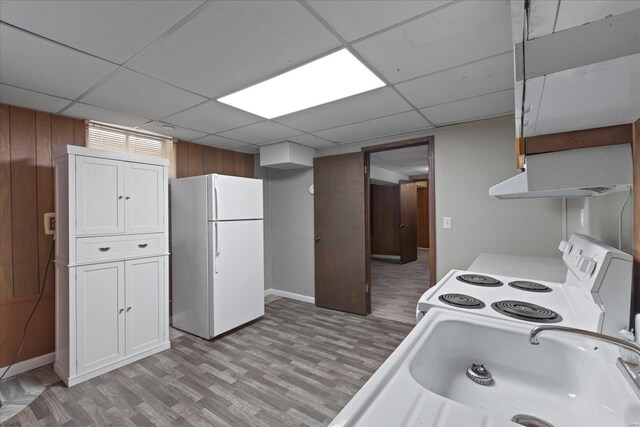 kitchen with white appliances, white cabinets, under cabinet range hood, light wood-style floors, and a sink
