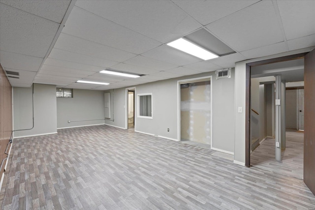 finished basement with a paneled ceiling, baseboards, visible vents, and wood finished floors