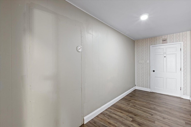 empty room with baseboards, wallpapered walls, and dark wood finished floors