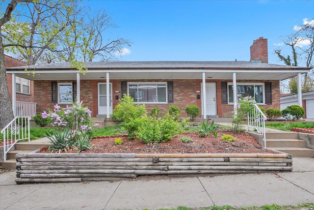 view of front facade with a porch, a chimney, and brick siding