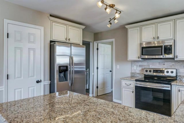 kitchen with tile patterned floors, light stone counters, backsplash, and appliances with stainless steel finishes