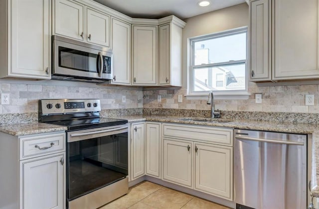 kitchen with tasteful backsplash, light tile patterned floors, stainless steel appliances, and a sink