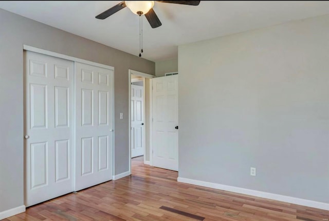 unfurnished bedroom with light wood-type flooring, a closet, a ceiling fan, and baseboards