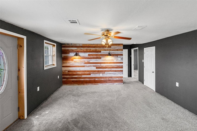 carpeted spare room featuring visible vents and ceiling fan