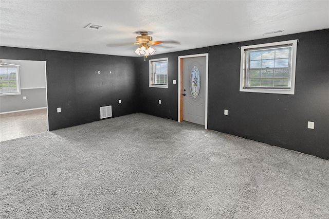 carpeted empty room featuring visible vents and ceiling fan