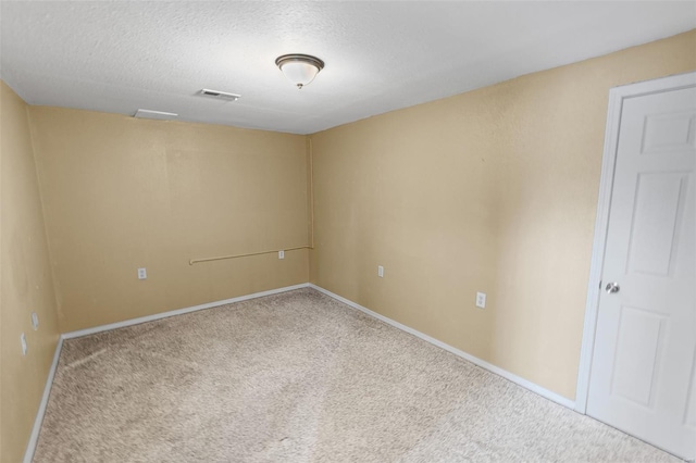 empty room with carpet, visible vents, a textured ceiling, and baseboards