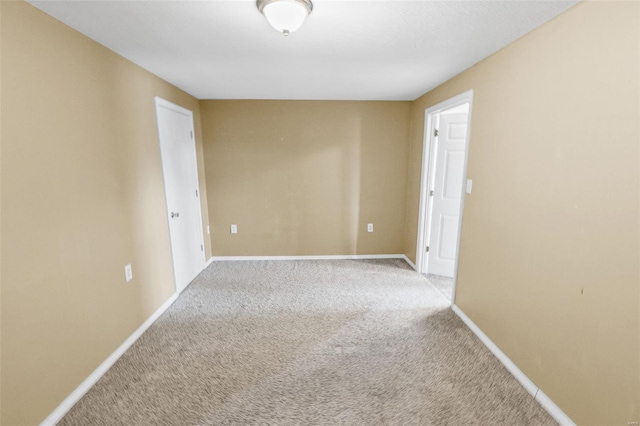 empty room featuring carpet flooring and baseboards