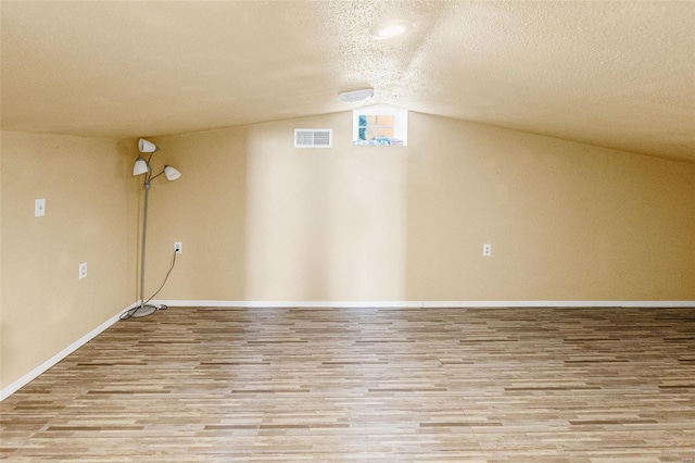 below grade area featuring wood finished floors, visible vents, baseboards, and a textured ceiling