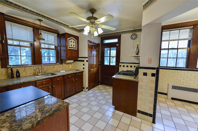 kitchen with hanging light fixtures, light tile patterned floors, a sink, ceiling fan, and radiator heating unit
