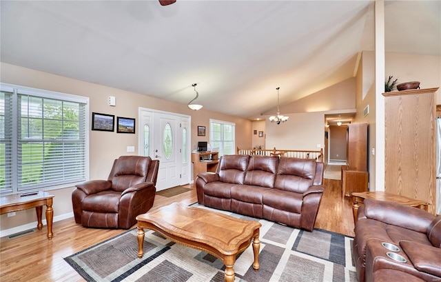 living area with a healthy amount of sunlight, an inviting chandelier, light wood finished floors, and lofted ceiling