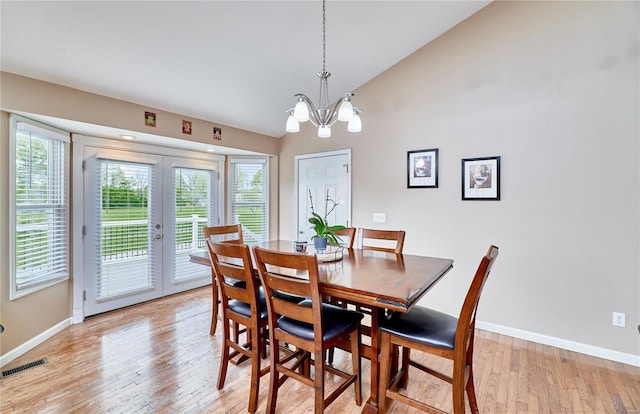 dining space featuring baseboards, visible vents, light wood finished floors, and vaulted ceiling