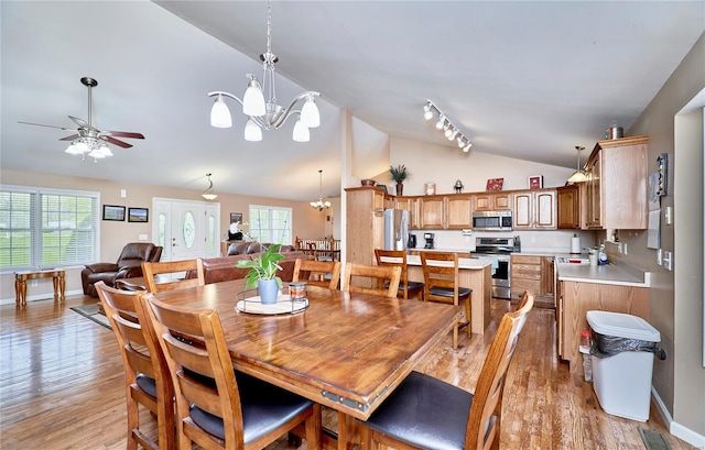 dining room featuring light wood-style flooring, baseboards, vaulted ceiling, and ceiling fan with notable chandelier