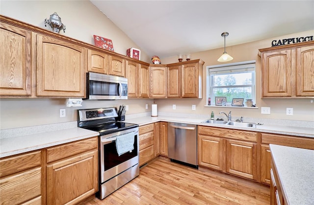 kitchen with pendant lighting, light wood-style floors, stainless steel appliances, light countertops, and vaulted ceiling