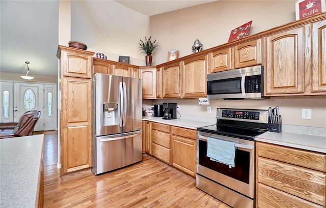 kitchen with stainless steel appliances, light countertops, and light wood finished floors