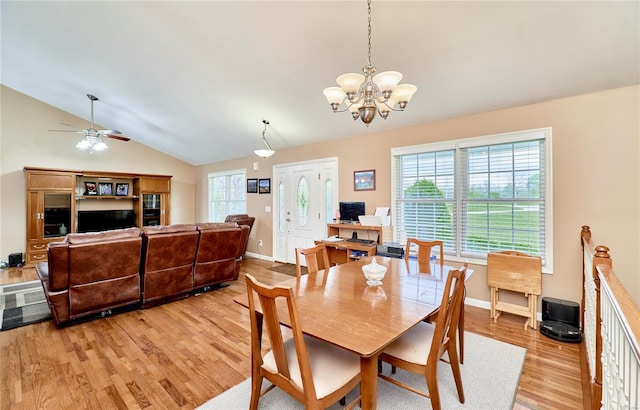 dining space featuring lofted ceiling, baseboards, light wood-style flooring, and ceiling fan with notable chandelier
