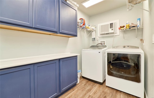 clothes washing area with separate washer and dryer, cabinet space, a wall mounted AC, and light wood-style floors