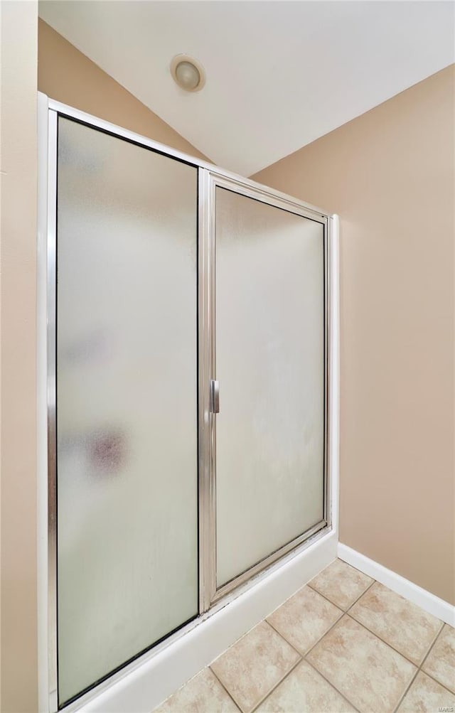 full bath with tile patterned floors, baseboards, a stall shower, and vaulted ceiling