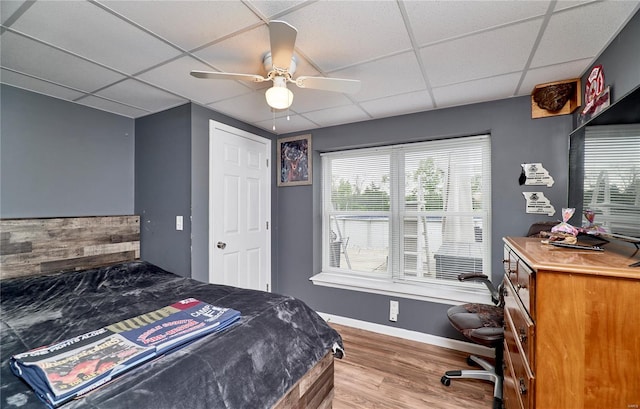 bedroom with a paneled ceiling, ceiling fan, wood finished floors, and baseboards