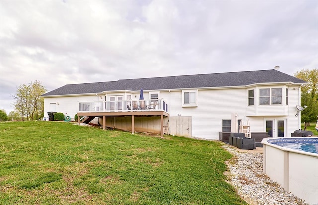rear view of property featuring a deck, french doors, a yard, and an outdoor pool