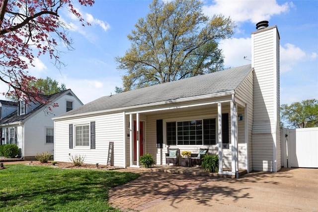 view of front of property featuring a porch, a front lawn, a chimney, and fence