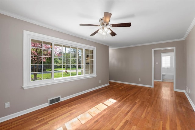 empty room with baseboards, visible vents, light wood-style floors, a ceiling fan, and crown molding