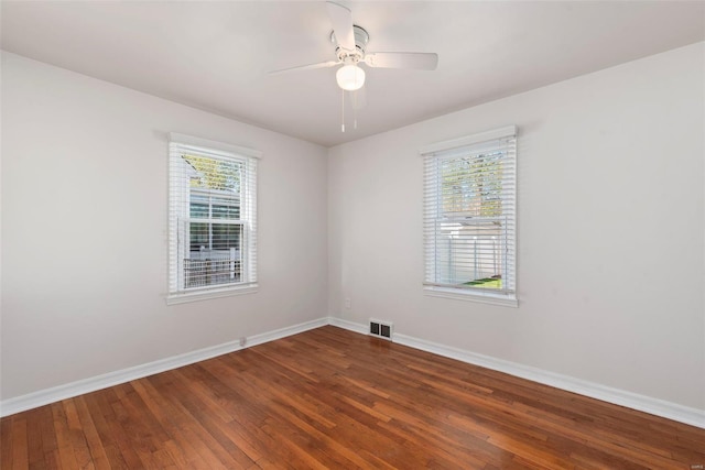 spare room featuring baseboards, wood finished floors, visible vents, and a ceiling fan