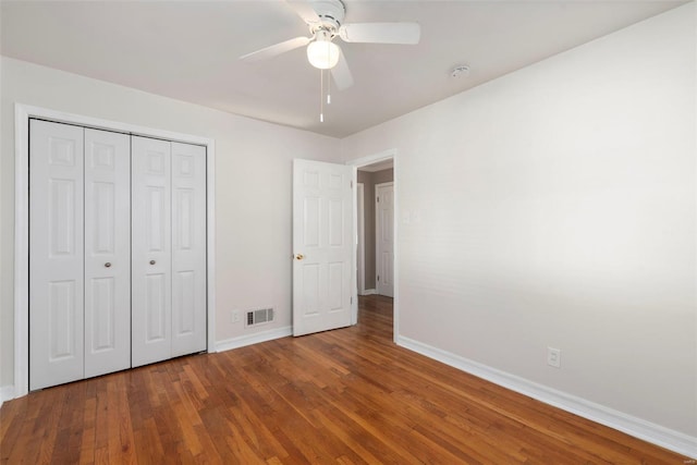unfurnished bedroom with wood finished floors, visible vents, a closet, baseboards, and ceiling fan