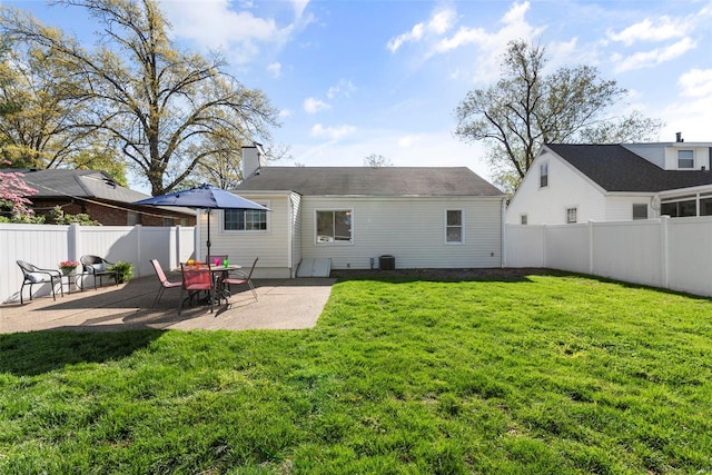 back of property with a patio area, a lawn, a chimney, and fence