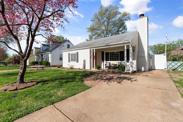 view of front of home featuring a chimney, a gate, fence, a porch, and a front yard