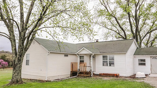 view of front facade featuring a front yard and a shingled roof