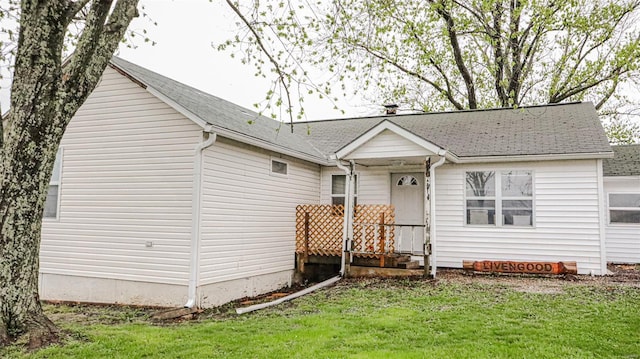 single story home featuring a front lawn and roof with shingles