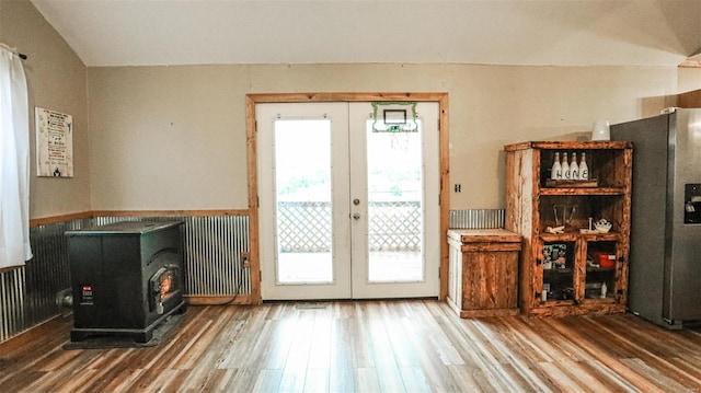 doorway to outside with french doors, wood finished floors, a wood stove, and wainscoting