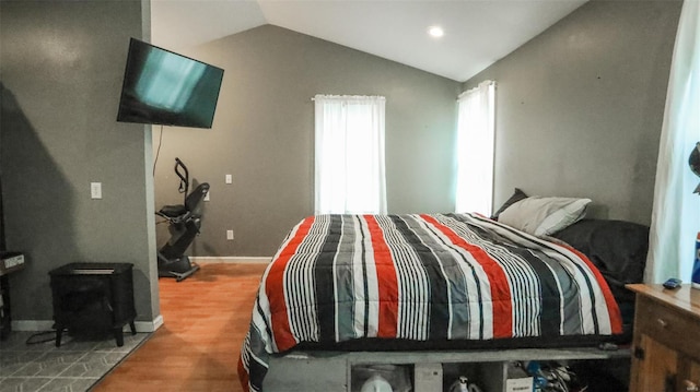 bedroom featuring recessed lighting, a wood stove, vaulted ceiling, and wood finished floors