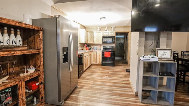 kitchen featuring a sink, light countertops, light wood-type flooring, and black appliances